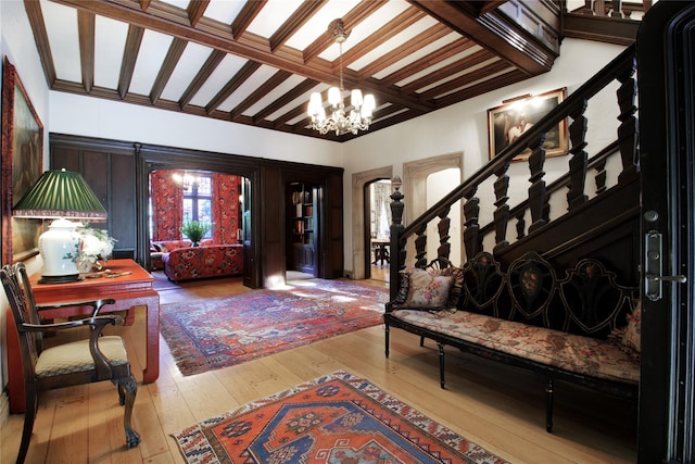 foyer featuring stairs, a chandelier, hardwood / wood-style floors, and beamed ceiling