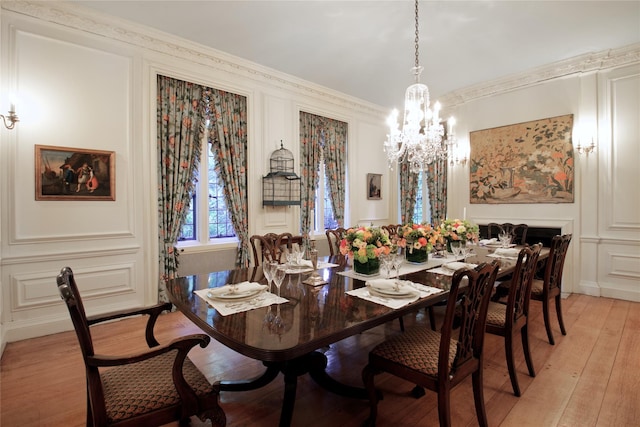 dining space with light wood-style floors, a decorative wall, and ornamental molding