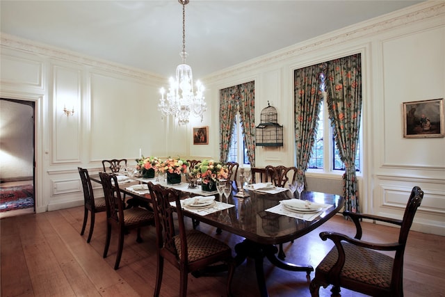 dining room featuring ornamental molding, light wood-type flooring, a notable chandelier, and a decorative wall