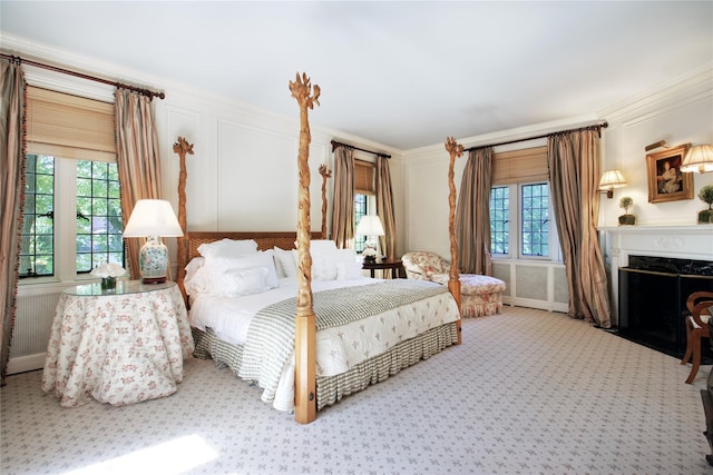 bedroom featuring ornamental molding, carpet, multiple windows, and a decorative wall