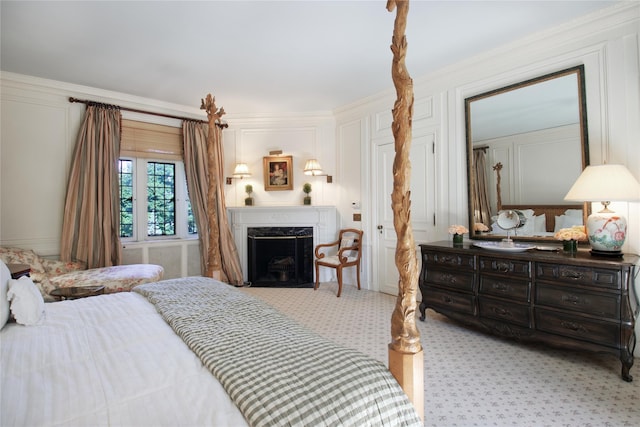 bedroom featuring crown molding, a high end fireplace, light carpet, and a decorative wall