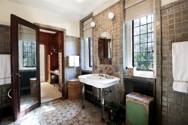 bathroom featuring brick floor, tile walls, and a healthy amount of sunlight