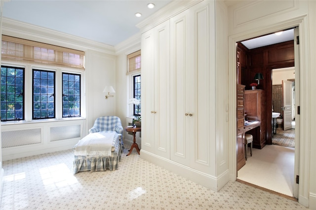 sitting room featuring light carpet, crown molding, and a decorative wall