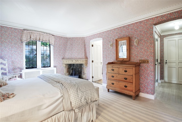 bedroom featuring baseboards, ornamental molding, a fireplace, and wallpapered walls