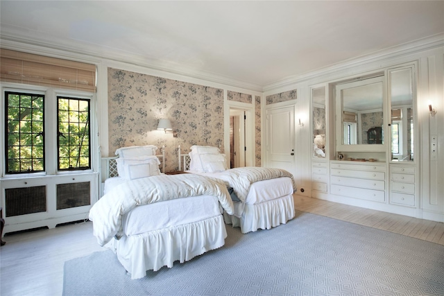 bedroom with wallpapered walls, crown molding, and wood finished floors