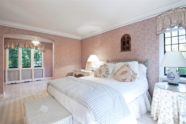 bedroom featuring wallpapered walls, a notable chandelier, and crown molding