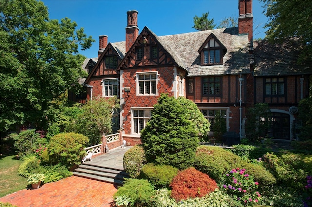 tudor home with brick siding and a chimney