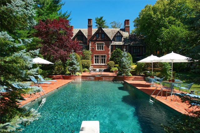 outdoor pool featuring a diving board and a patio area