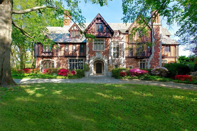 107 Bayview Rd, Manhasset, NY 11030 - tudor house with a chimney, a front lawn, a high end roof, and brick siding