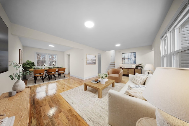 living room featuring plenty of natural light, stairway, baseboards, and wood finished floors