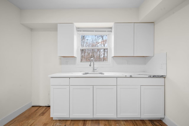 kitchen with light countertops, light wood-style floors, a sink, and white cabinets