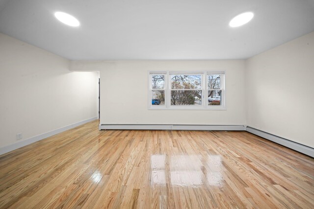 unfurnished room with baseboards, baseboard heating, and wood finished floors