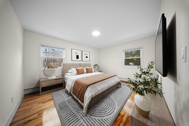 bedroom featuring multiple windows, light wood-style flooring, and baseboards