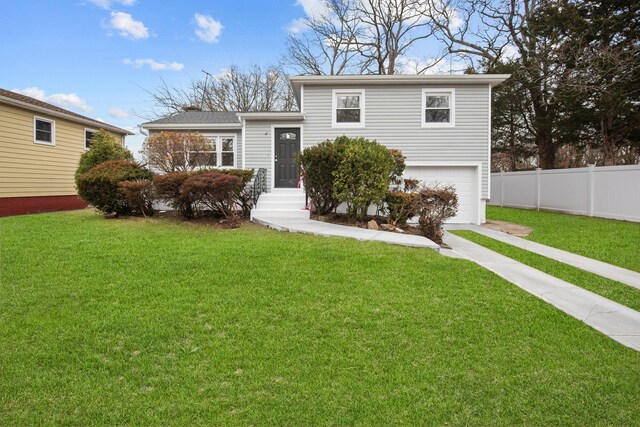 split level home featuring a front yard, fence, driveway, and an attached garage