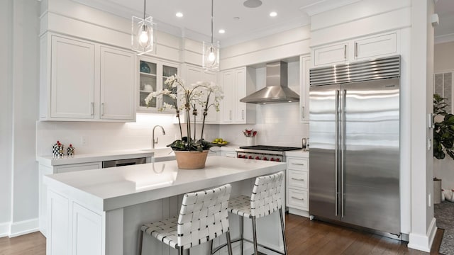 kitchen featuring wall chimney range hood, tasteful backsplash, appliances with stainless steel finishes, and a sink