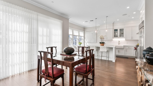 dining room with recessed lighting, crown molding, and wood finished floors