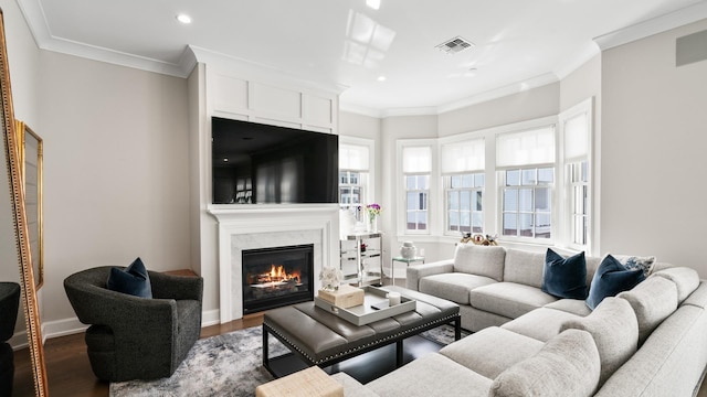 living area featuring baseboards, visible vents, a premium fireplace, ornamental molding, and wood finished floors