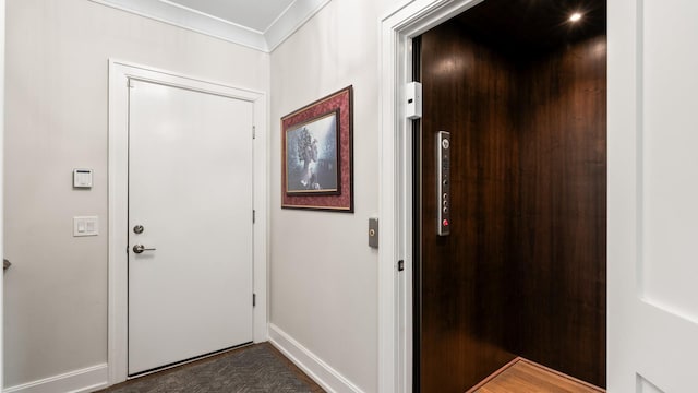 foyer with elevator, crown molding, and baseboards