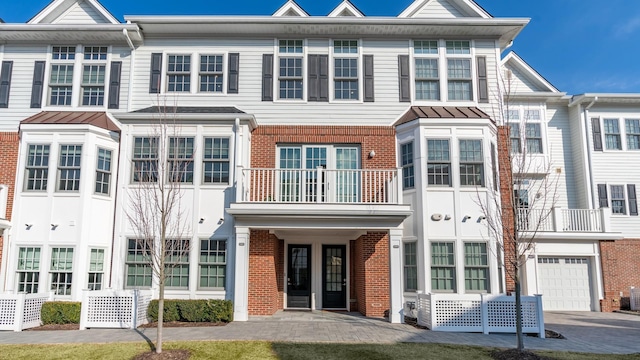 multi unit property featuring a garage, brick siding, and driveway