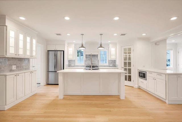 kitchen with light wood-type flooring, white cabinetry, appliances with stainless steel finishes, and light countertops