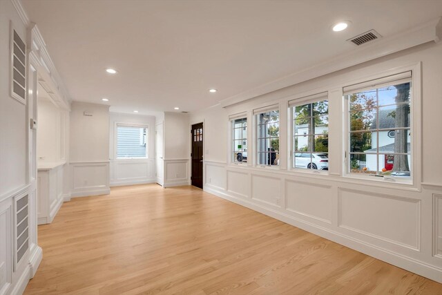 spare room featuring light wood-style floors, visible vents, a decorative wall, and recessed lighting