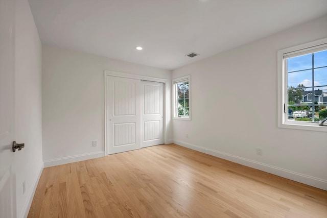 unfurnished bedroom featuring visible vents, light wood-style flooring, and baseboards