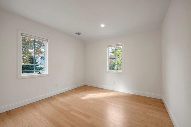 empty room with light wood-style floors, recessed lighting, visible vents, and baseboards