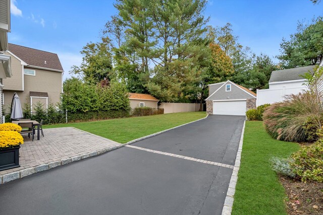 exterior space with a garage, a patio area, fence, and an outbuilding