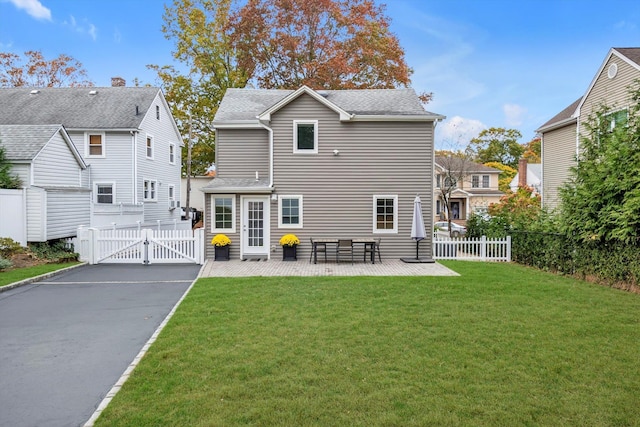 rear view of house with a gate, a yard, fence, and a patio