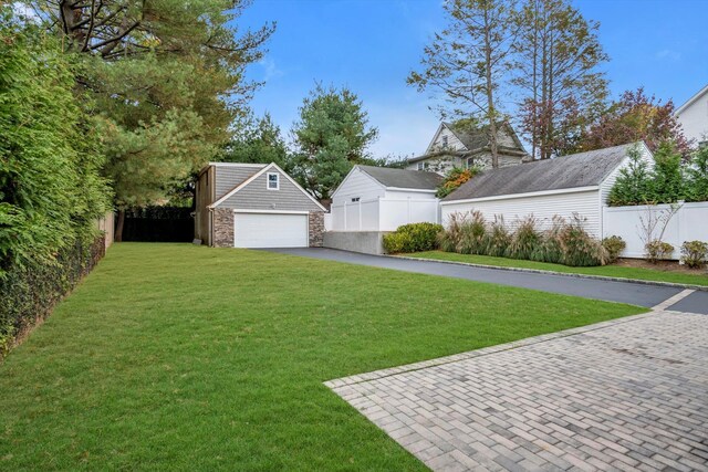 view of yard with driveway, an outdoor structure, and fence private yard