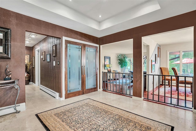 entryway with baseboards, a baseboard heating unit, and a raised ceiling