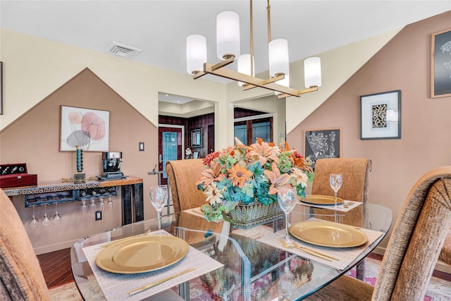 dining area featuring a chandelier, visible vents, baseboards, and wood finished floors