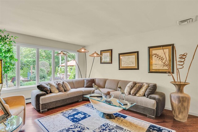 living area featuring visible vents, baseboard heating, and wood finished floors