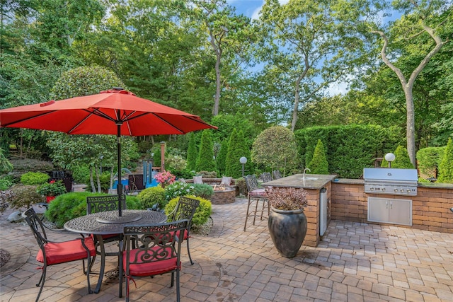 view of patio with an outdoor fire pit, outdoor dining area, a grill, and an outdoor kitchen