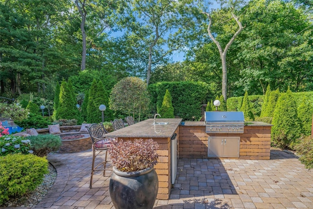 view of patio featuring an outdoor fire pit, an outdoor kitchen, area for grilling, a sink, and outdoor dry bar