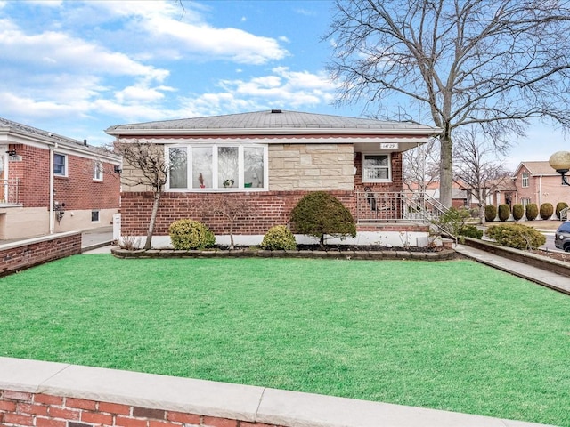 view of front of home with a front lawn, brick siding, and stone siding