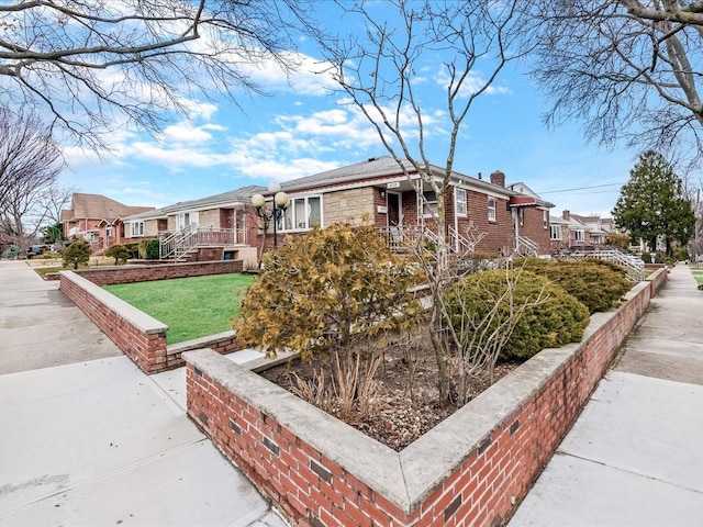 ranch-style home with brick siding, a residential view, stone siding, and a chimney