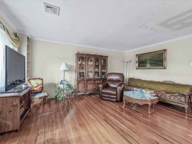 living area featuring visible vents, crown molding, and wood finished floors