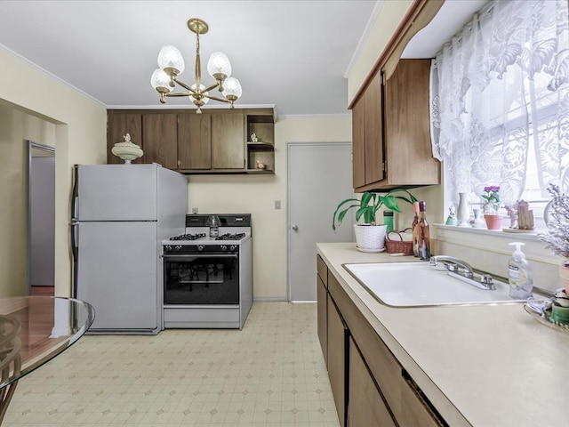 kitchen featuring a sink, light floors, freestanding refrigerator, light countertops, and white range with gas stovetop