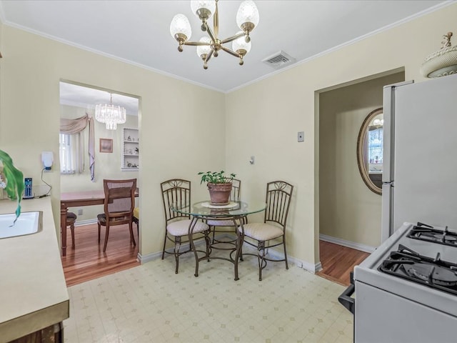 dining room featuring an inviting chandelier, light floors, visible vents, and ornamental molding