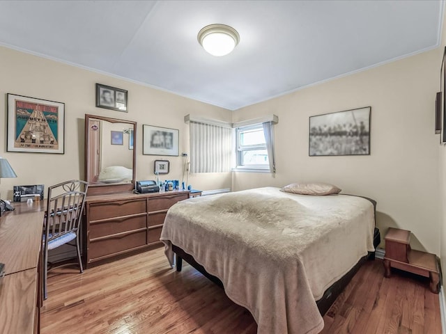 bedroom with light wood-style floors and crown molding