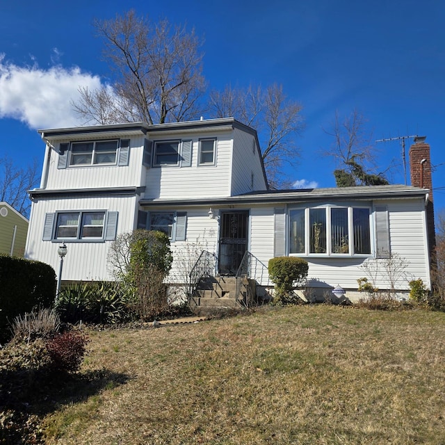 view of front of property with a chimney and a front lawn