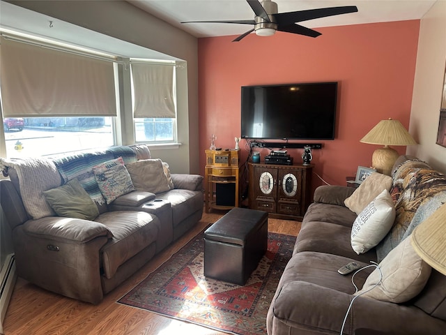 living room with a baseboard heating unit, ceiling fan, and wood finished floors