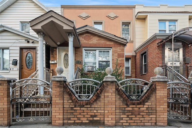 view of front facade with a fenced front yard, brick siding, and a gate