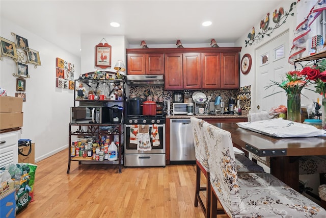 kitchen with light wood-style flooring, under cabinet range hood, tasteful backsplash, recessed lighting, and stainless steel appliances