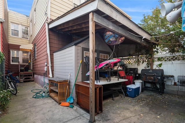 view of patio / terrace with area for grilling, a storage shed, an outdoor structure, and fence
