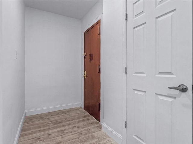 corridor featuring light wood finished floors and baseboards