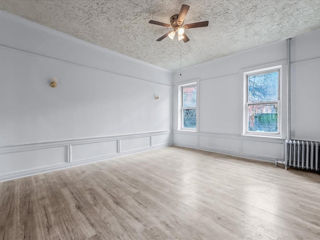 spare room with radiator, ceiling fan, a textured ceiling, and wood finished floors