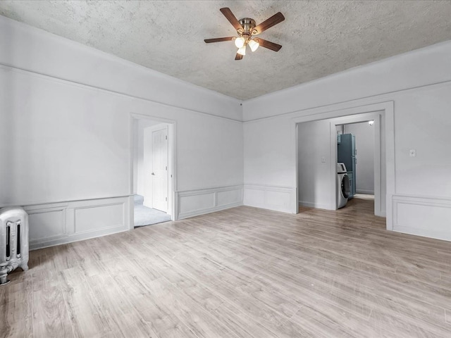 empty room featuring light wood-style flooring, a decorative wall, a textured ceiling, and a ceiling fan