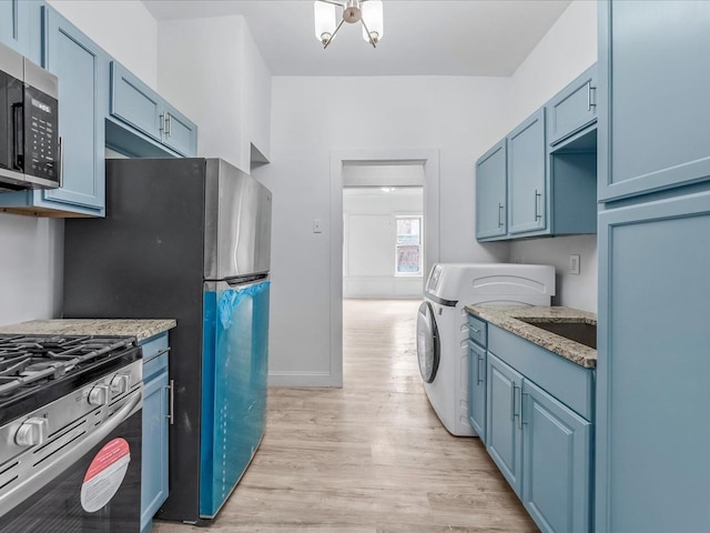 kitchen with light stone counters, blue cabinetry, light wood finished floors, stainless steel appliances, and washer / dryer